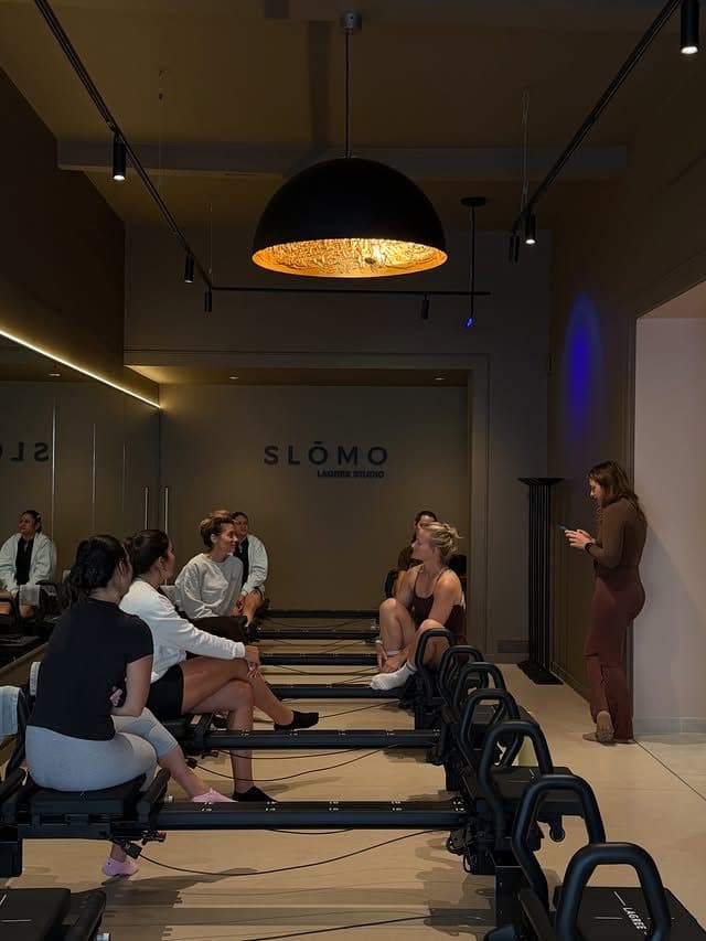 Stagiaires assises sur les Micro Pro, à l'écoute de la formatrice, devant le logo SLŌMO