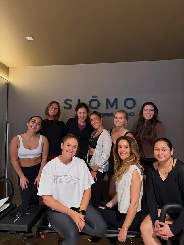 Photo de groupe des participantes de la certification Lagree Level 1 devant le logo SLŌMO